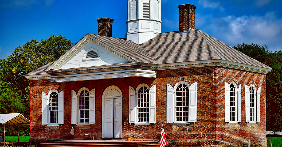 Colonial-style brick building with shutters and cupola in Williamsburg, USA.