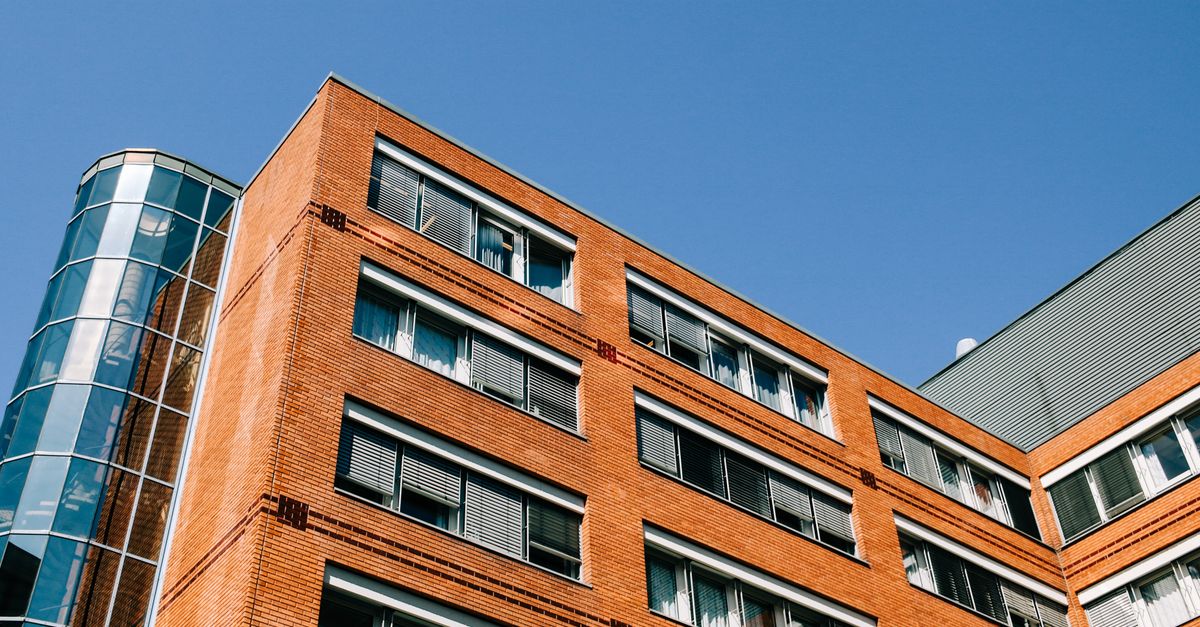 From below of contemporary high apartment building located in residential district against blue sky