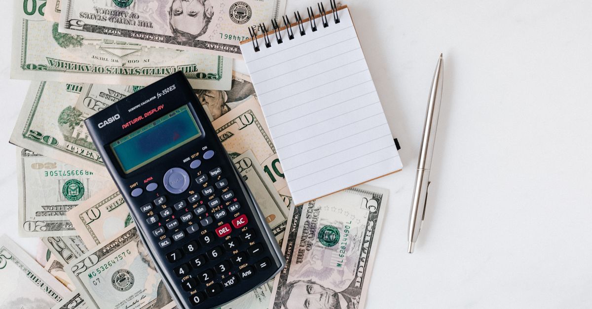 Top view of electronic calculator and notepad placed over United States dollar cash money together with metallic pen for budget planning and calculation