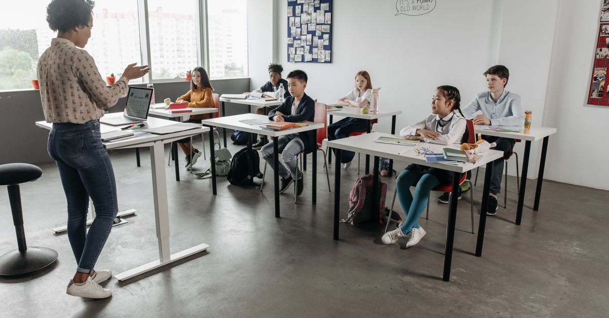 Teacher interacting with students in a modern classroom, fostering a diverse and engaging educational environment.