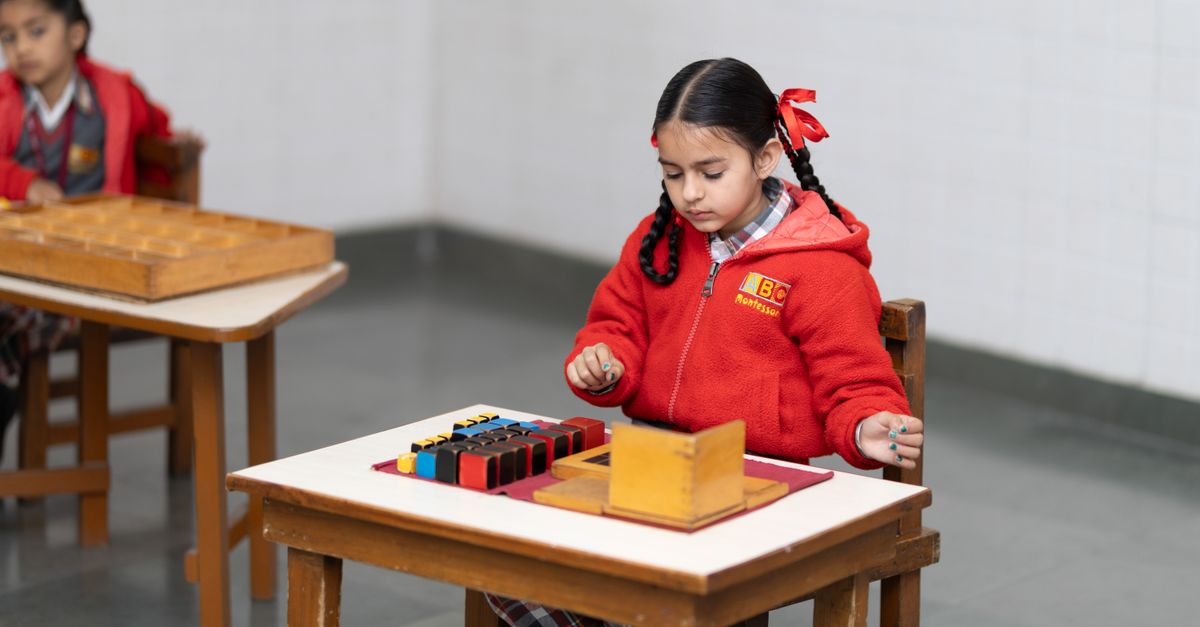 A young girl in a classroom focused on a Montessori educational activity with colorful blocks.