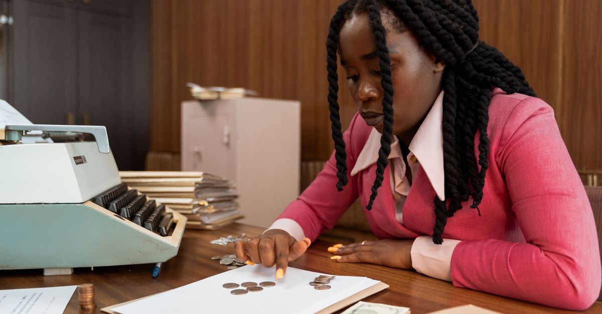 A businesswoman in vintage attire counts coins in a retro office setting.